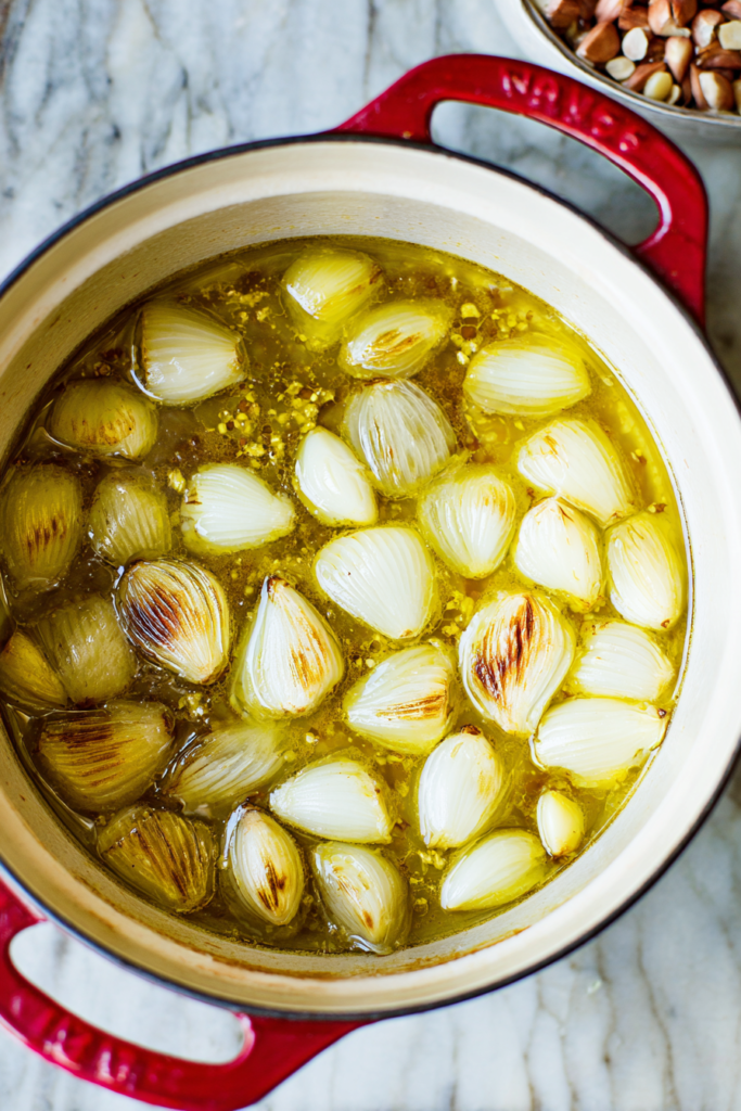 Braising liquid with broth, vinegar, and aromatics in a Dutch oven